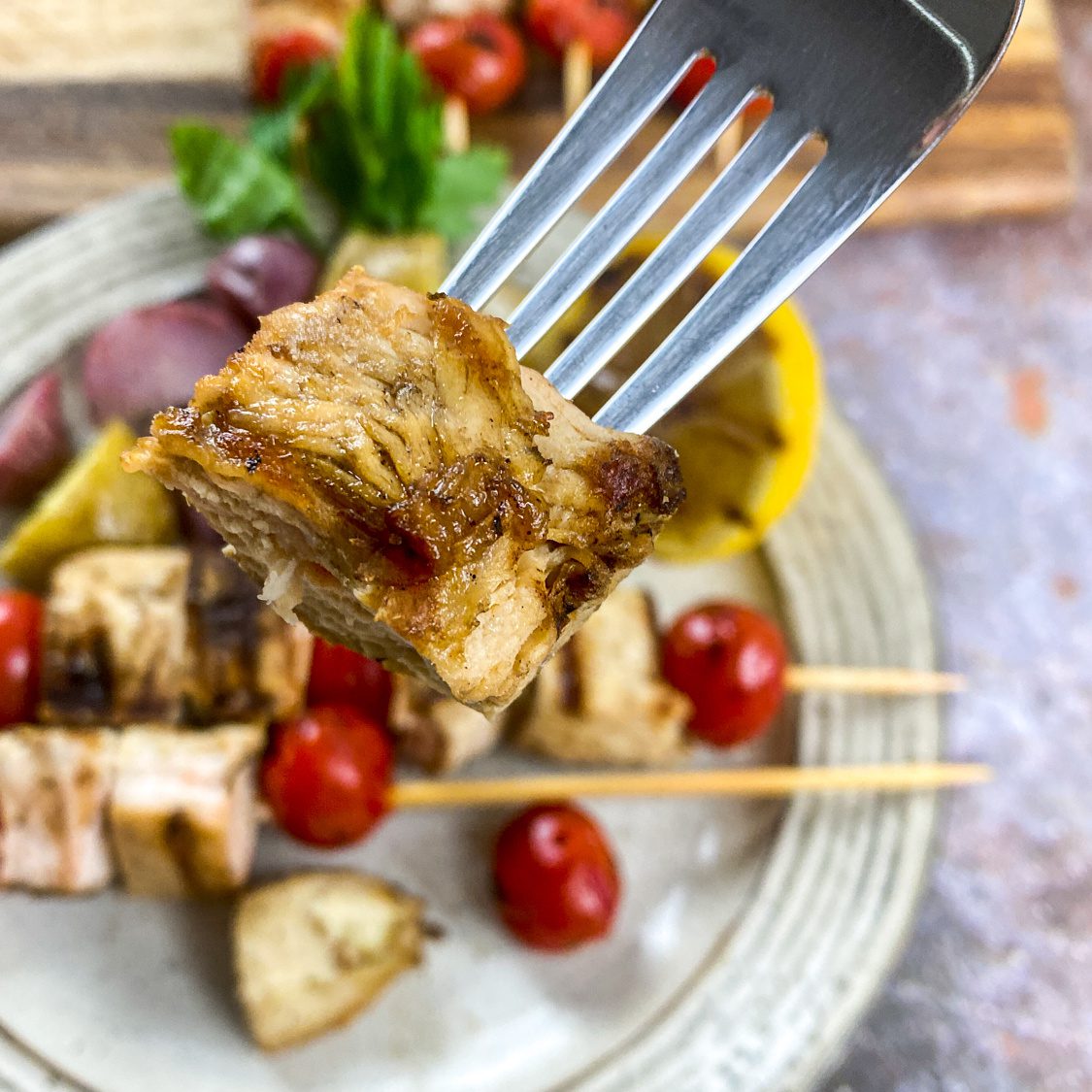 Grilled Greek chicken skewers with tomatoes and lemon on a plate