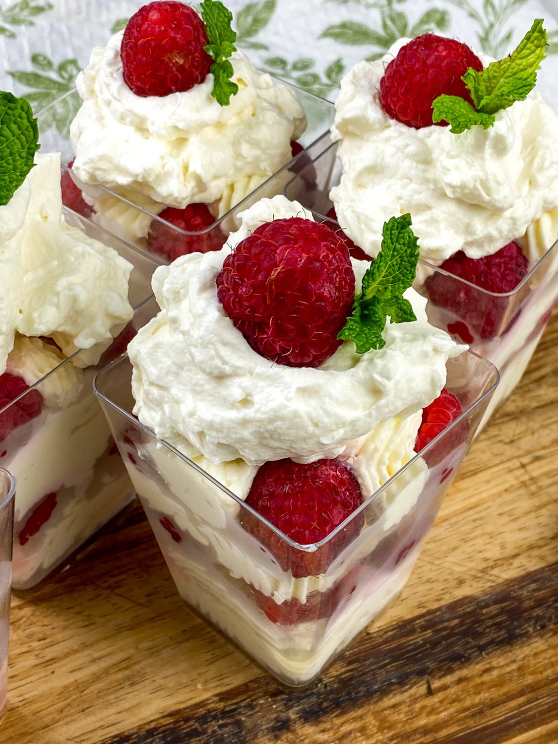 No bake lemon raspberry cheesecake cups in individual dessert cups with whipped cream and mint