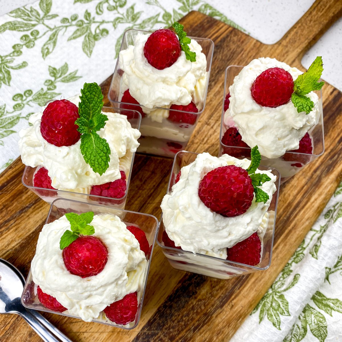 No bake lemon raspberry cheesecake cups in individual dessert cups with whipped cream and mint