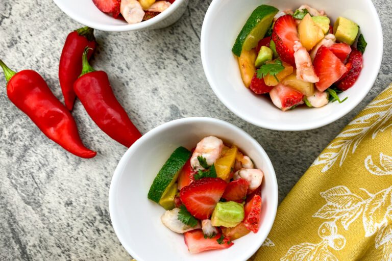 Bowl of colorful strawberry shrimp ceviche with lime wedges