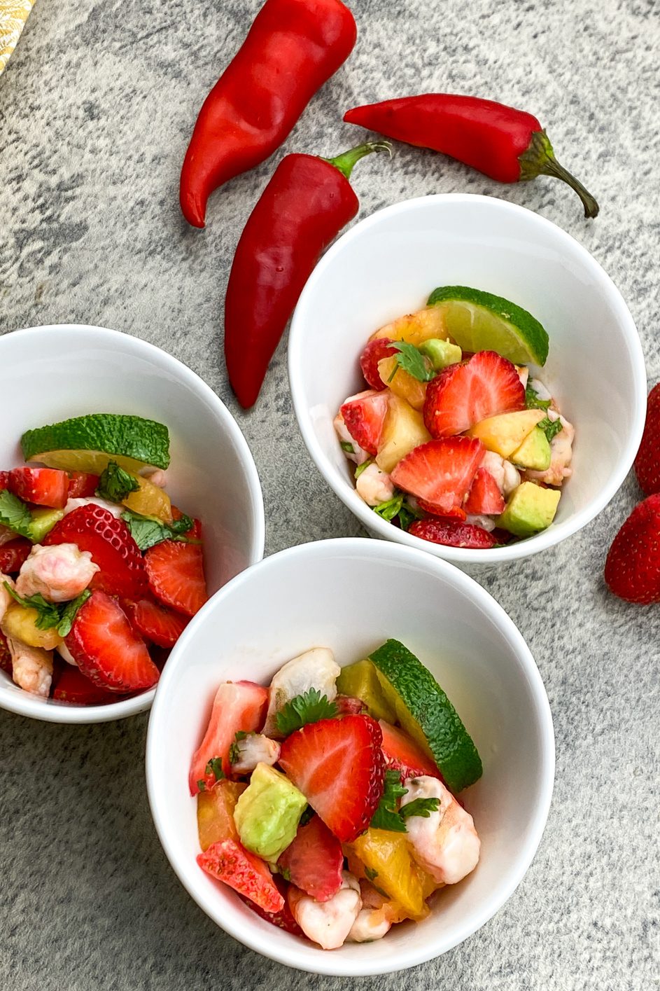 Bowl of colorful strawberry shrimp ceviche with lime wedges