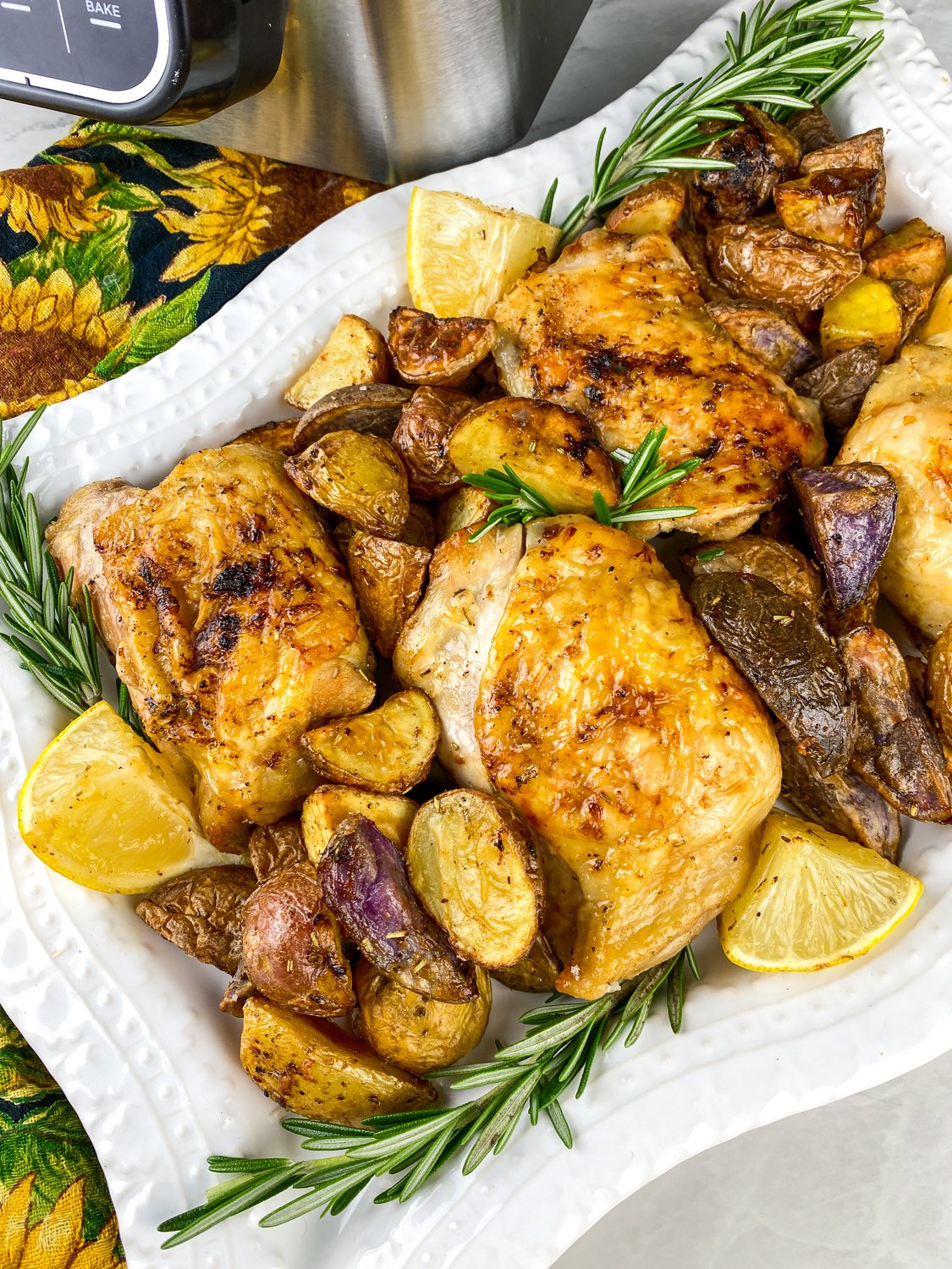 Crispy lemon rosemary chicken thighs with grilled lemon wedges on a serving platter