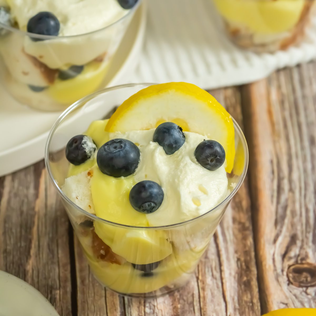 Individual blueberry lemon trifles topped with whipped cream and lemon slices