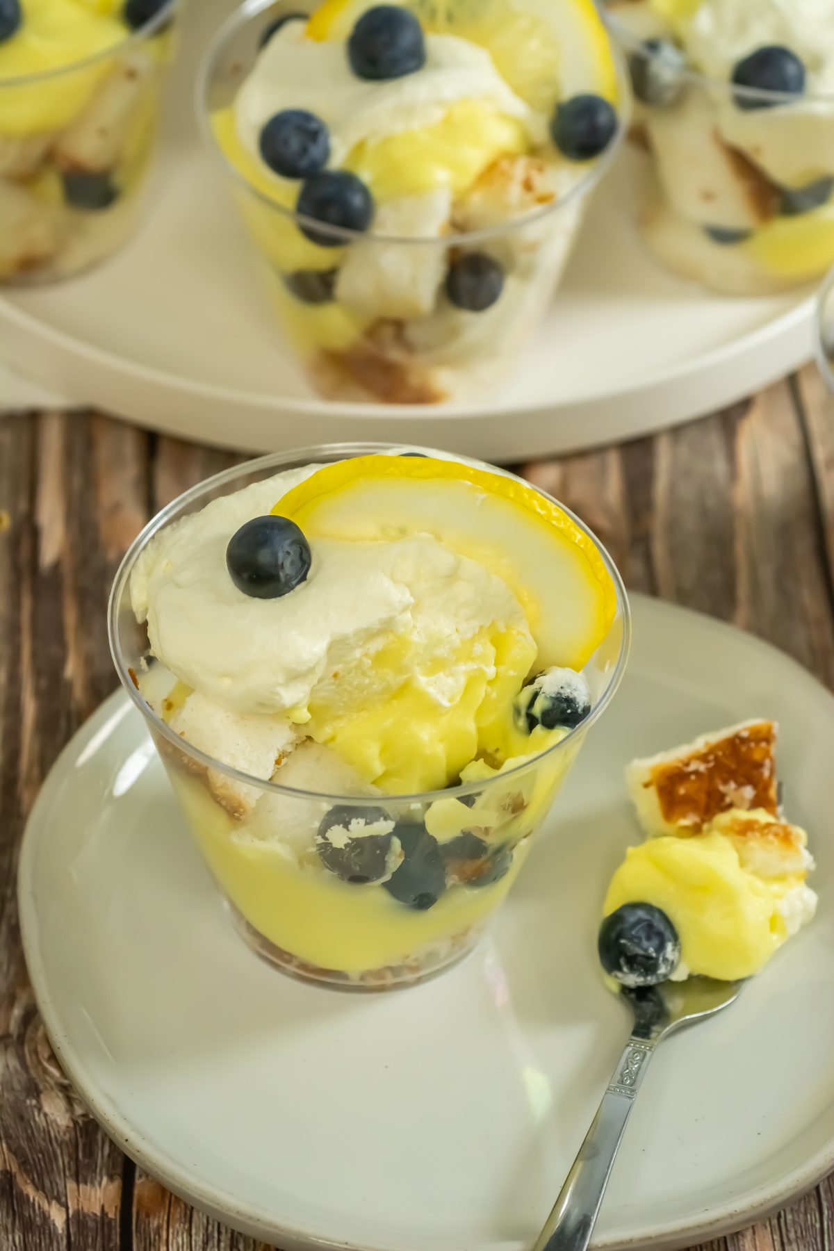 Individual blueberry lemon trifles topped with whipped cream and lemon slices