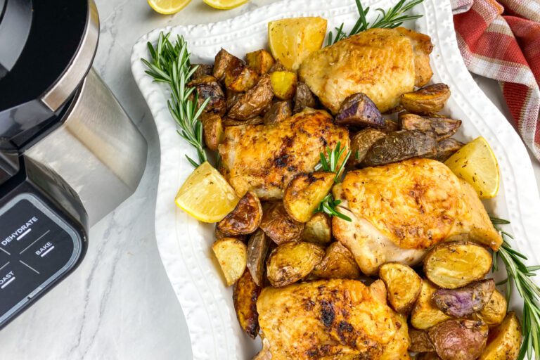 Crispy lemon rosemary chicken thighs with grilled lemon wedges on a serving platter