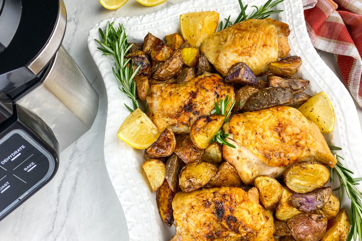 Crispy lemon rosemary chicken thighs with grilled lemon wedges on a serving platter