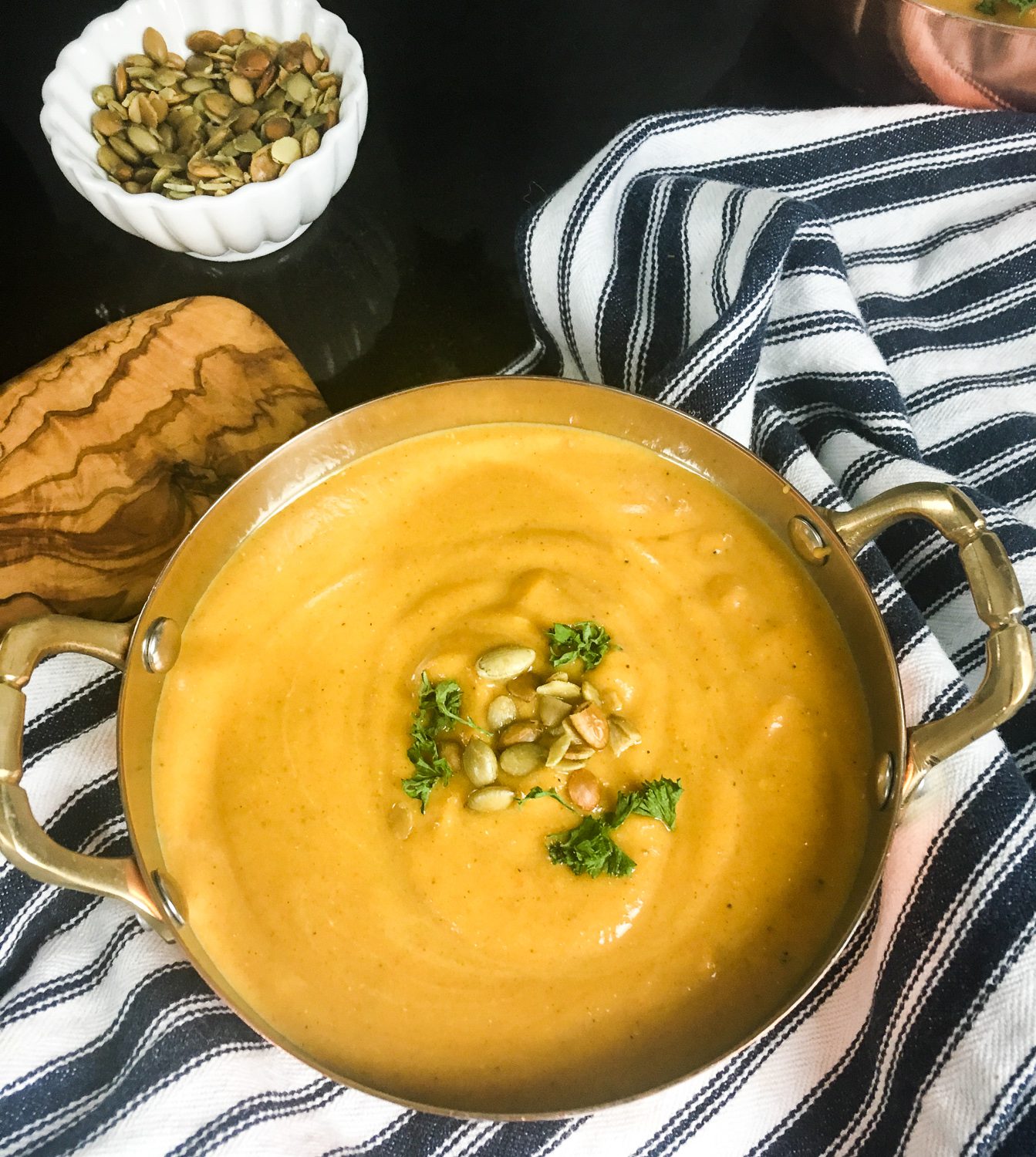 Curried butternut squash soup in bowl topped with pumpkin seeds