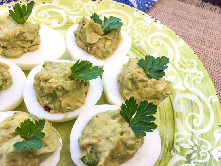 Avocado deviled eggs on platter topped with fresh parsley