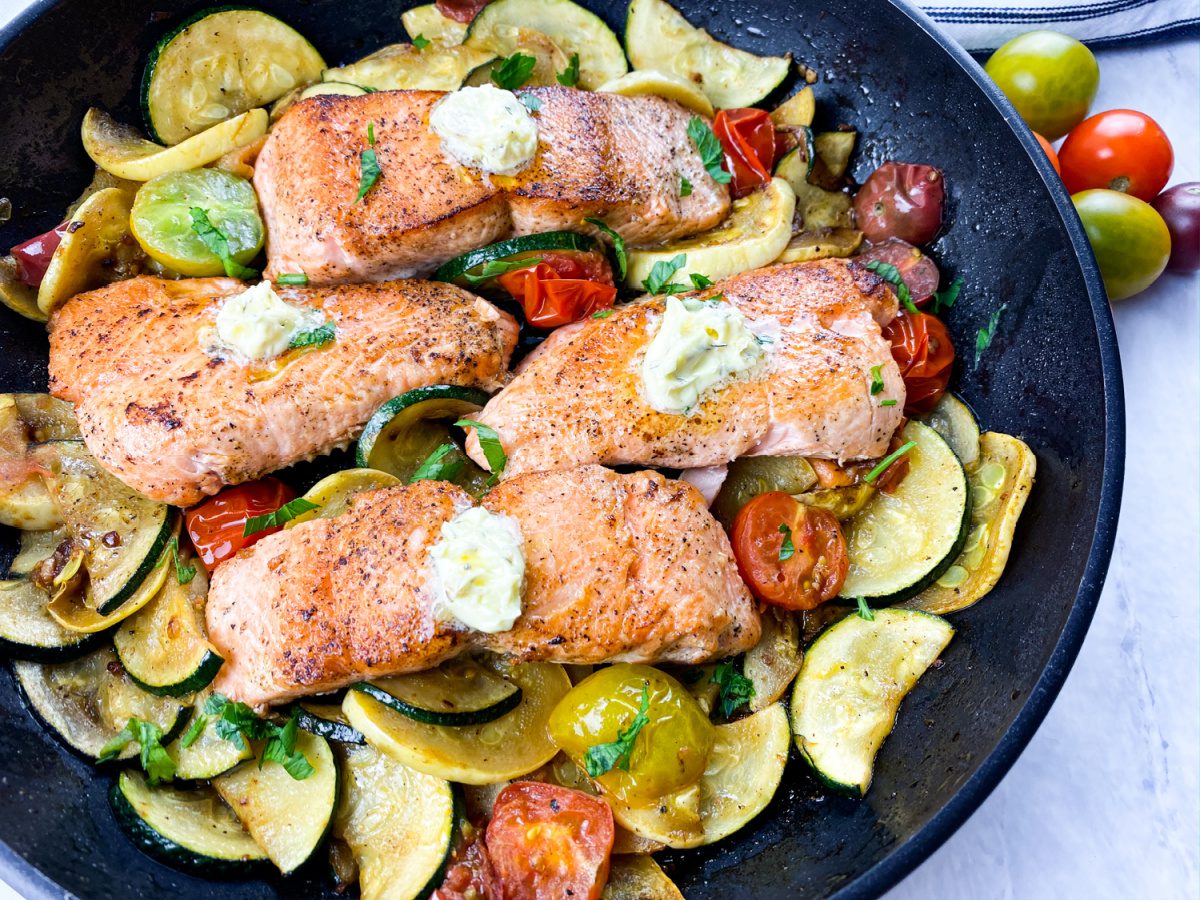 "Crispy skin salmon fillets topped with herb butter and sautéed vegetables"
