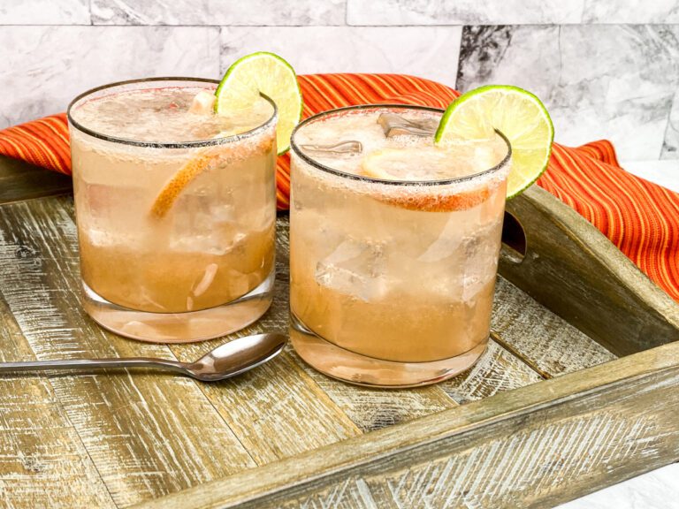 Two sparkling Paloma cocktails on a wood serving tray