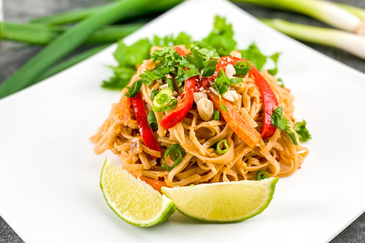 Vegetable pad Thai with peanuts and lime wedges