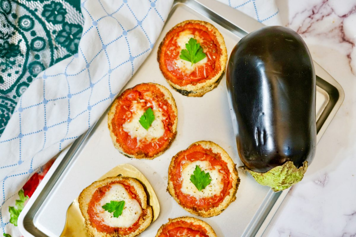 Crispy breaded eggplant slices topped with marinara and melted mozzarella on sheet pan