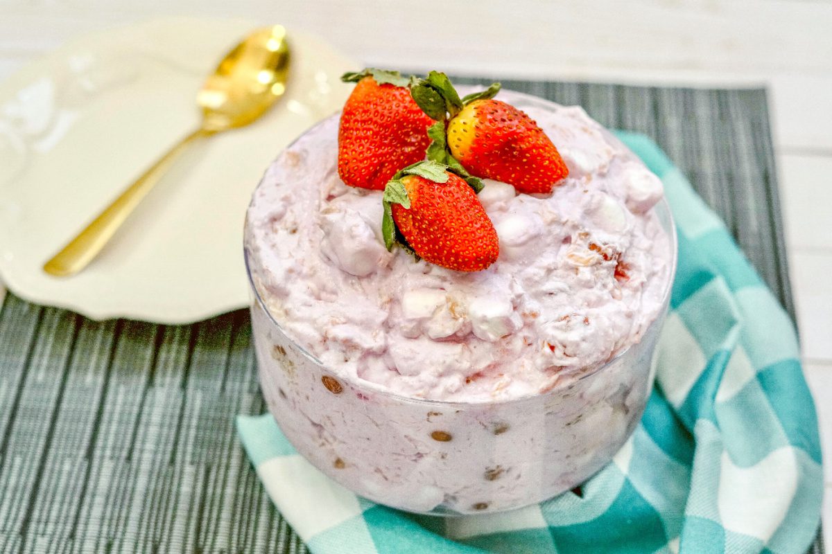 Strawberry fluff salad in serving bowl garnished with fresh strawberries